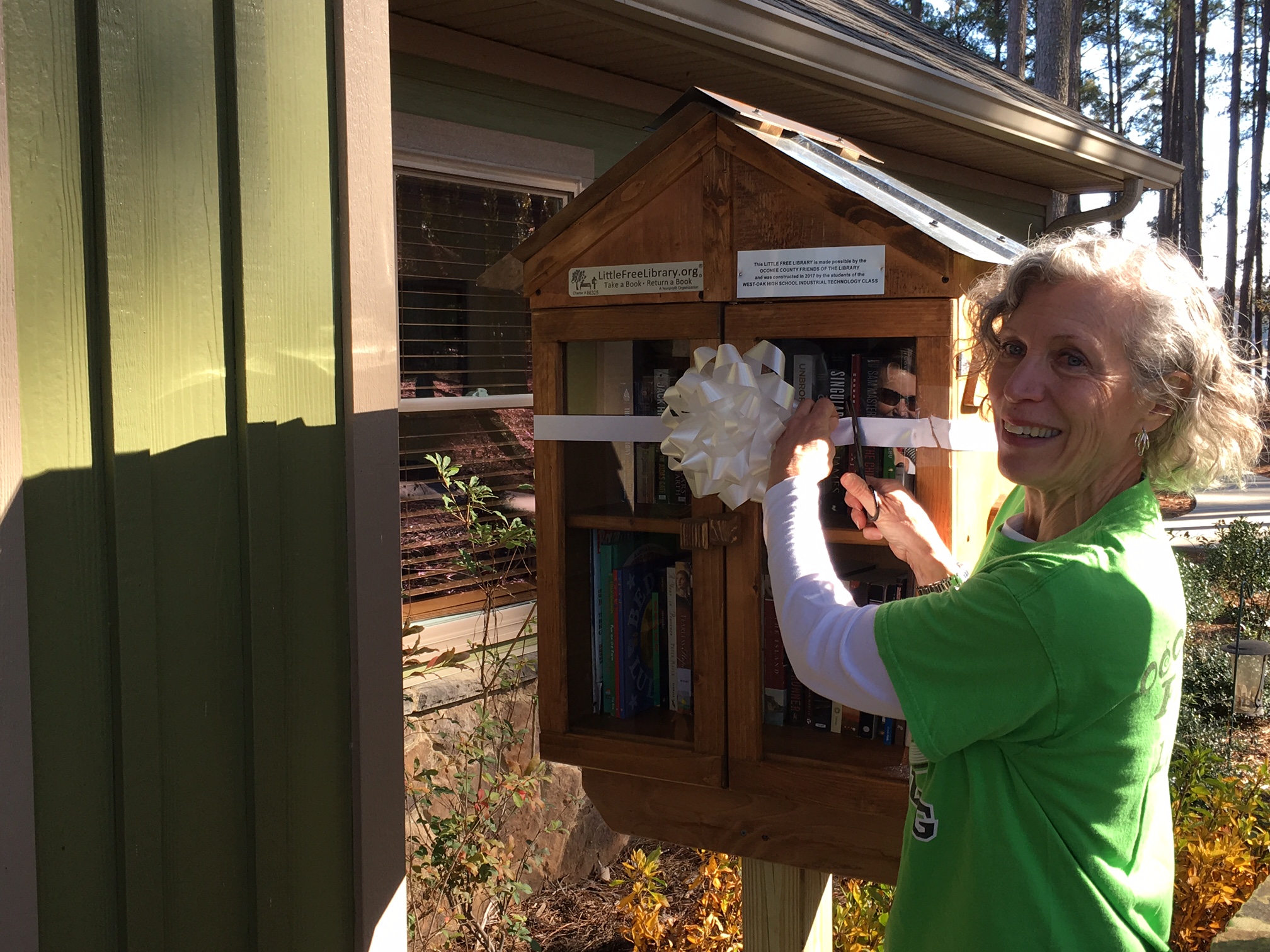 A Friends member cutting the ribbon on a new Little Free Library.